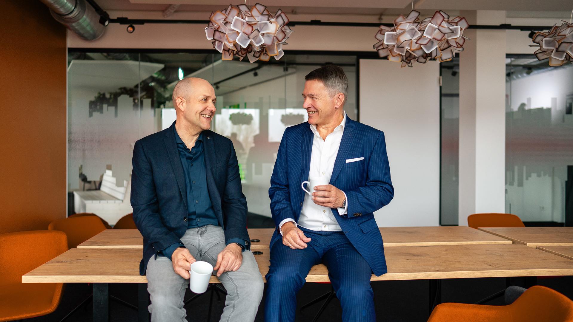 Martin Kohlsaat (Vortstand cink AG) und Robert Fink (Geschäftsführer akquinet business consulting GmbH) nebeneinander auf einem Tisch sitzend und über S/4HANA diskutierend.