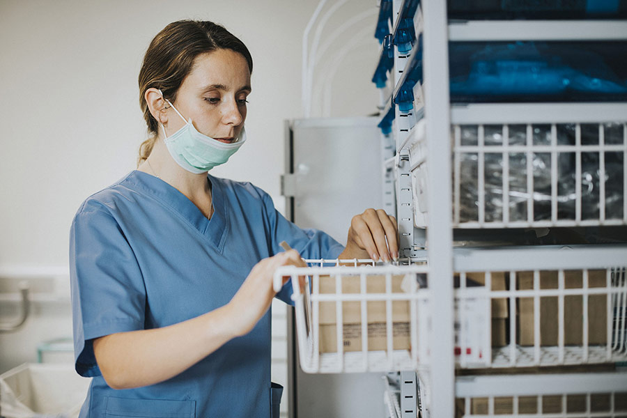 Krankenschwester schaut im Regal nach Medikamenten